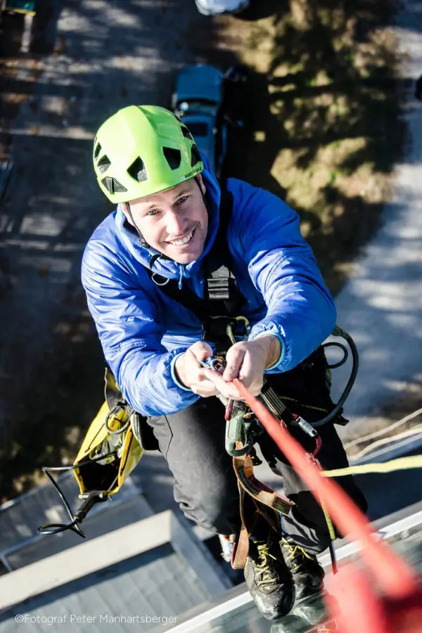 Klaus Jöchler am Seil mit Helm und blauer Jacke beim Fensterputzen